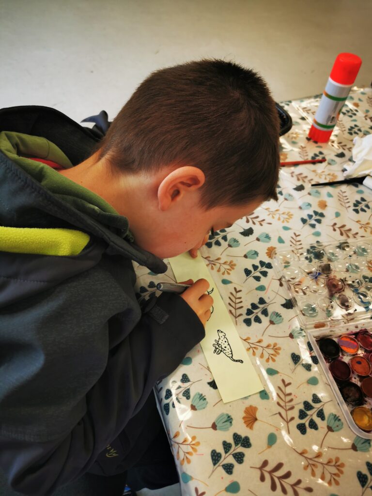 Child painting at an arts and crafts table with paints and brushes