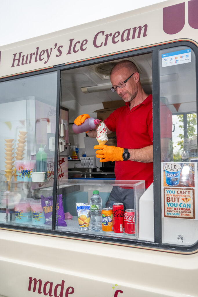 Man serving an ice cream cone from a Hurley’s Ice Cream stand